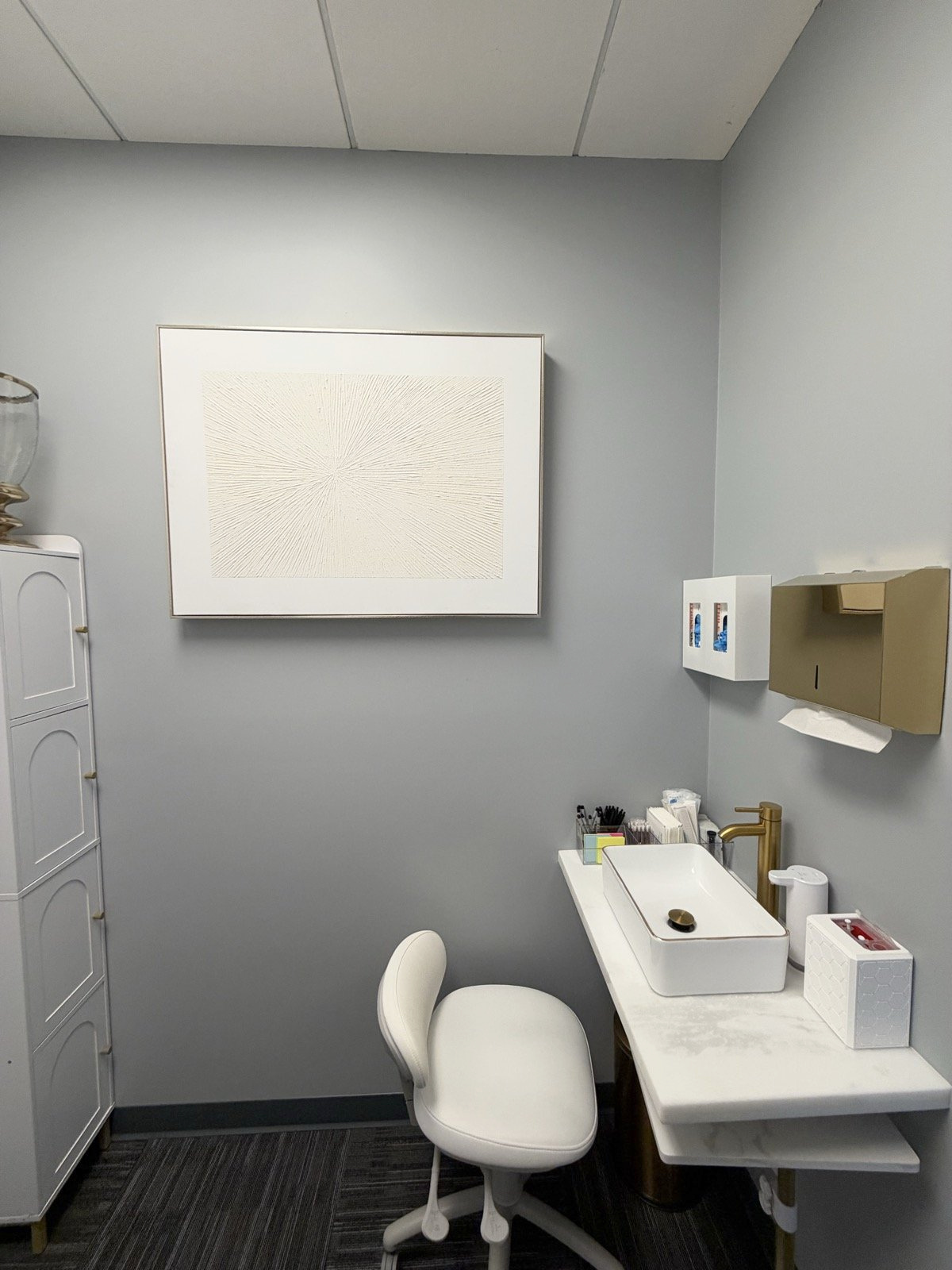 Private clinic care room with a sink, care cart, and stool