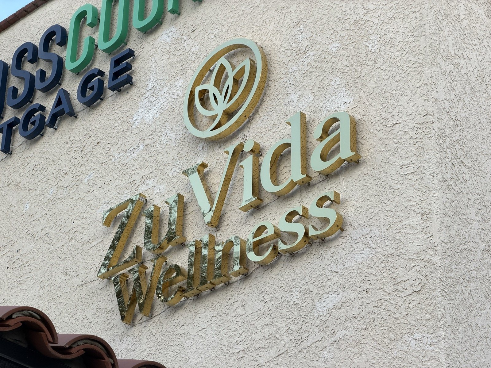The gold ZuVida Wellness sign on the clinic’s exterior stucco wall