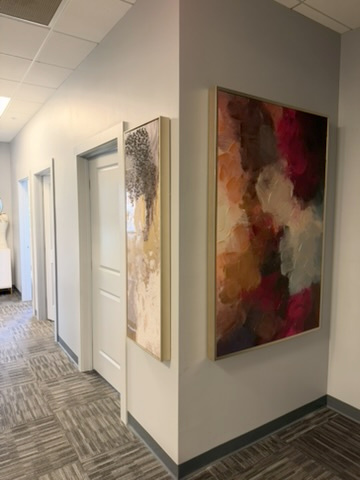 ZuVida hallway with gold-framed abstract artwork and private room doors
