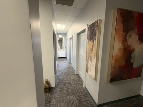 View down the ZuVida clinic hallway with framed artwork and gray patterned carpet