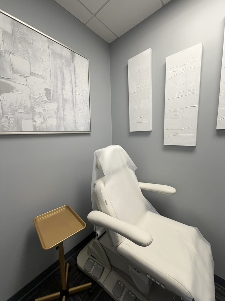 Private ZuVida treatment room with an ivory reclining chair, gray walls, and framed artwork
