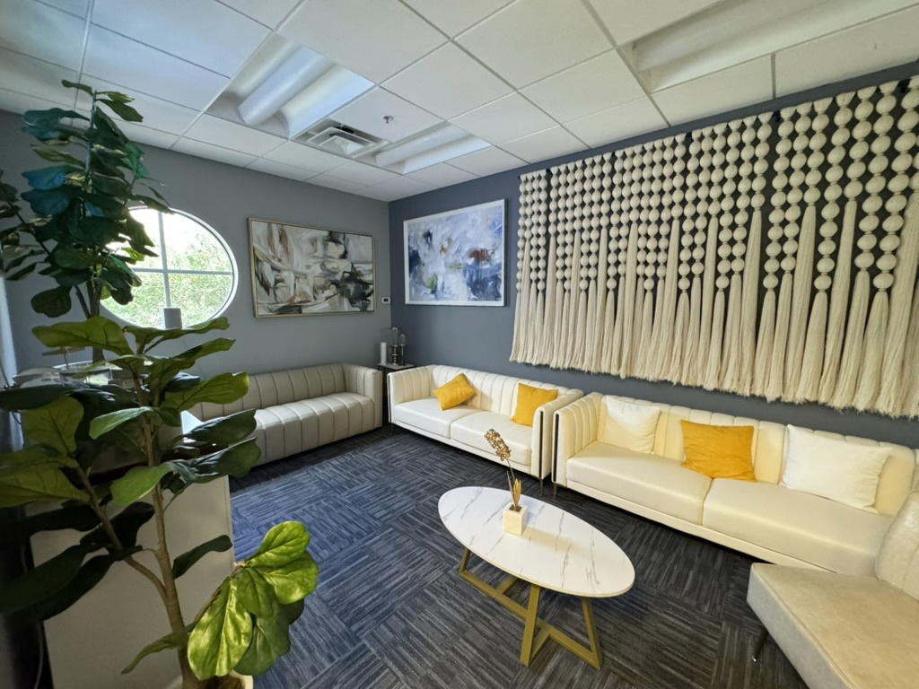ZuVida waiting room with ivory sofas, a round table, plants, and natural light